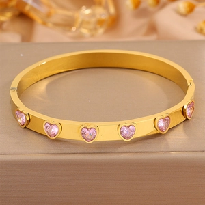 Détail d'un bracelet en acier doré orné de zircons roses en forme de cœur