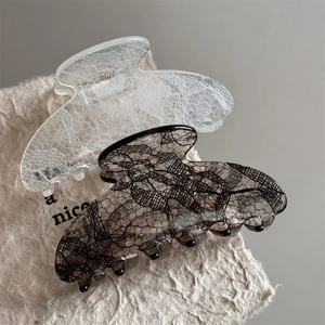 Detailed view of medium lace pattern hair claw clips in black and white classic colors