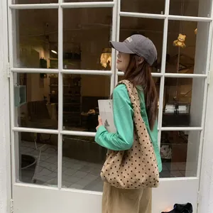 Polka dot canvas tote bag in khaki and coffee brown worn over the shoulder outdoors