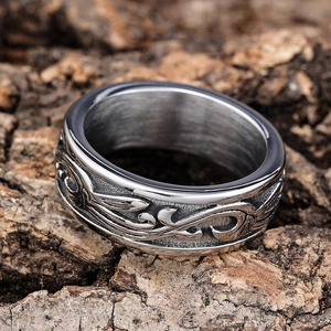 Macro shot of silver stainless steel ring with vine pattern on rough tree bark texture