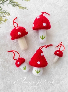 Flat lay of five red polka dot wool felt mushroom ornaments with hanging strings