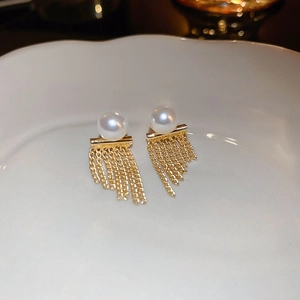 Detailed macro view of vintage gold tassel earrings with pearls on a white plate
