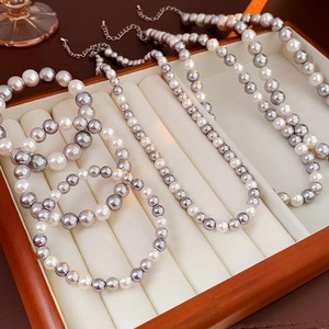 Macro view of white and grey pearl necklaces and bracelets in a wooden jewelry tray