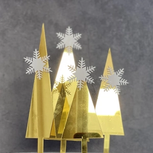 Detailed view of golden mirror acrylic Christmas tree cake toppers with white snowflakes