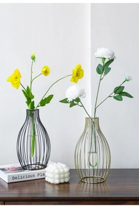 Detail of modern black and gold lantern vases with glass tube inserts and faux flowers