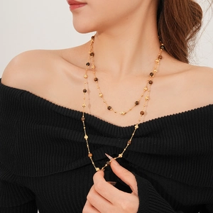 Close-up of gold-plated double-layer necklace with brown tiger eye beads on a model