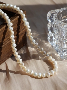 Detailed view of elegant freshwater pearl necklace draped over a dark wooden gift box