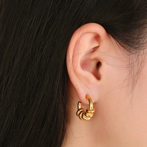 Détail de boucles d'oreilles spirales multicouches dorées portées par un mannequin