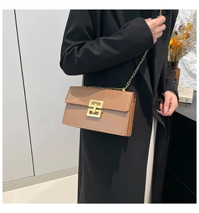 Detail view of the khaki leather crossbody bag featuring gold geometric metal buckle and chain