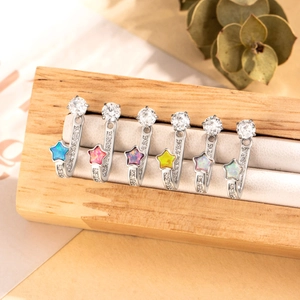 Set of six titanium steel star opal earrings with sparkling crystals on a wooden stand