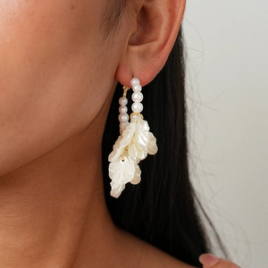Détail des boucles d'oreilles pétales de perles portées montrant une texture élégante