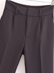 Detailed view of high-waist pleated black dress pants featuring clean seams and pocket design