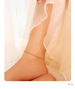 Detail of a thin 18K gold plated braided rope anklet worn on a female foot with soft veil