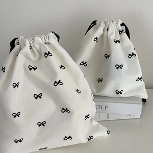 Minimalist white canvas drawstring bags with black ribbon bow print in two sizes