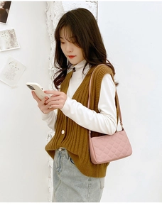 Detail of pink quilted shoulder bag with fine stitching and zip closure on model