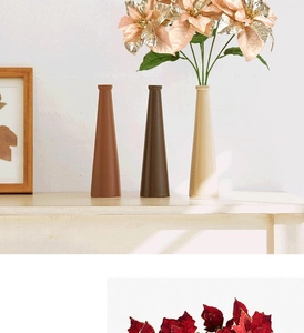 Detailed view of beige ceramic vase with pink and gold artificial poinsettia flowers