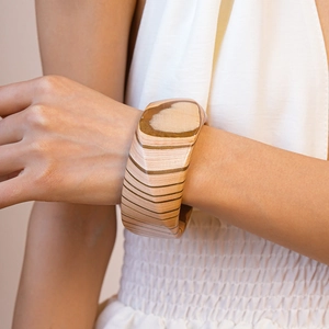 Detailed view of wide geometric wooden bracelet with natural grain on female wrist
