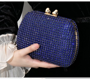 Detailed view of blue rhinestone evening clutch bag with gold heart-shaped metal clasps