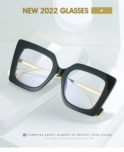 Detail of square black frame glasses with gold metal hinges on a white stand
