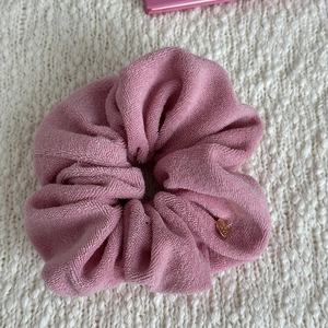 Detailed close-up of pink terry cloth headband with gold charm on knit background