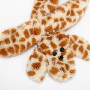 Detail of plush giraffe print scarf featuring soft faux fur texture and cute black pom-poms