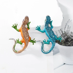 Detail of colorful crystal lizard brooches in orange and blue on a stone surface