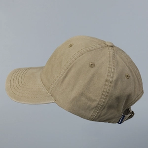 Detail of adjustable metal strap and blue logo label on a khaki cotton baseball cap
