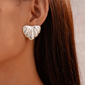 Close-up of silver acrylic heart stud earring with vertical textured ridges on a model