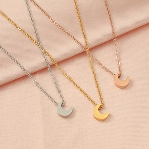 Three crescent moon pendant necklaces in silver, gold and rose gold on pink silk fabric