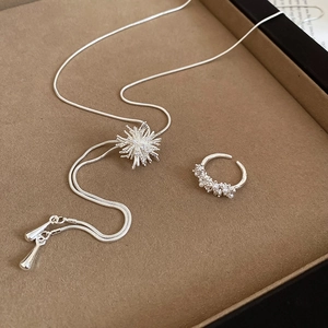 Detailed view of silver zircon firework necklace and pearl open ring set on a tray