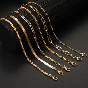 Detail of 6 different golden link chains on black leather display including Cuban and Figaro