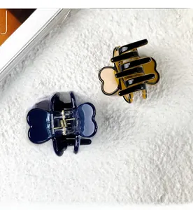 Detailed view of acetate clover hair clips in navy blue and tortoiseshell patterns