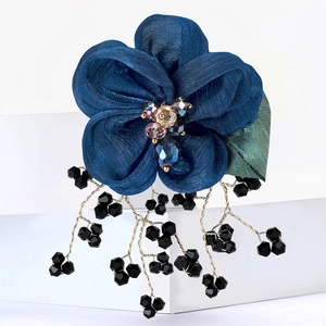 Detail of blue lace flower brooch with crystal core and elegant black tassel beads