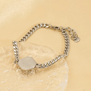 Détail d'un bracelet gourmette argenté avec plaque octogonale et fermoir mousqueton