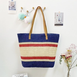 Detail of striped straw tote bag with brown leather handles in a cozy home setting