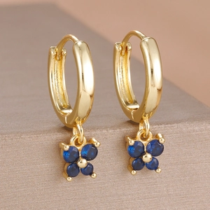 Détail macro de boucles d'oreilles dorées avec pétales en zircon bleu foncé élégants