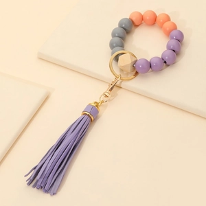 Detailed close-up of a beaded wristlet keychain with purple leather tassel and gold ring