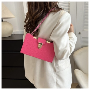 Detail of rose red quilted shoulder bag with gold chain strap worn by a model