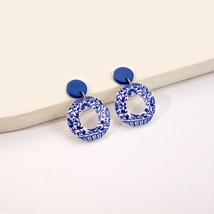 Macro detail of round blue and white porcelain pattern earrings on a minimalist display