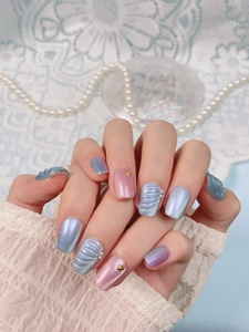 Close-up of ocean-themed press-on nails with blue-pink gradient and 3D shell textures