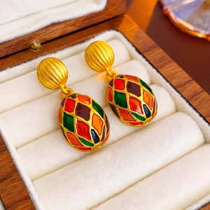 Detail of vintage gold earrings with colorful enamel diamond pattern on egg-shaped pendants
