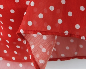 Detailaufnahme von rotem Chiffonstoff mit weißen Punkten und feiner Saumverarbeitung