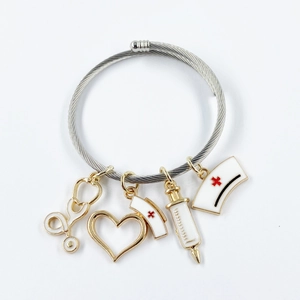 Silver bangle with gold medical charms including stethoscope and syringe on white background