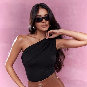 Slim fit one-shoulder black knit top paired with a brown leather skirt on a pink background