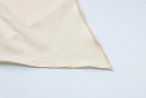 Detailaufnahme der beigen Textur und der hochwertig gesäumten Kantennaht des Stoffes