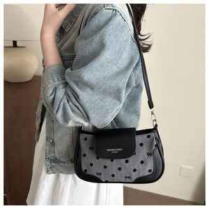 Sac à bandoulière à pois avec nœud porté par un mannequin dans un cadre intérieur