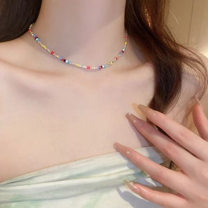 Close-up of colorful beaded choker necklace with gold metallic accents on model's neck