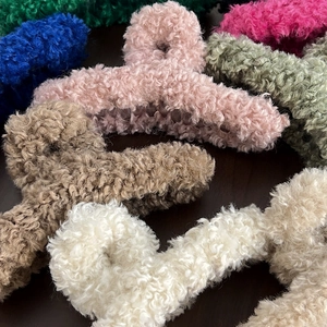 Plush faux fur hair claws in various colors like pink and brown for elegant hair styling