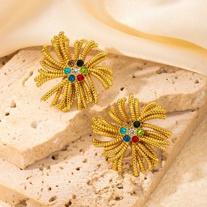Macro shot of gold fan-shaped stud earrings with colorful zircons on silk background