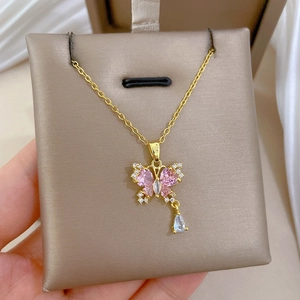 Dettaglio della collana dorata con zircone a farfalla rosa e pendente in cristallo a goccia